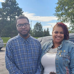 Mom and son standing in front of car wearing blue
